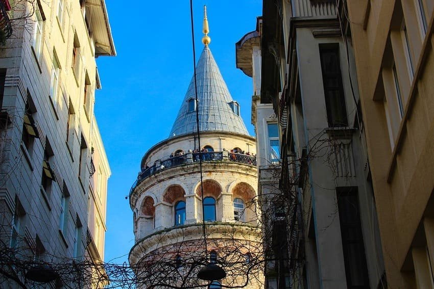 Widok na wieżę Galata z wąskiej uliczki w historycznej dzielnicy, z błękitnym niebem i średniowieczną architekturą genueńską Stambuł