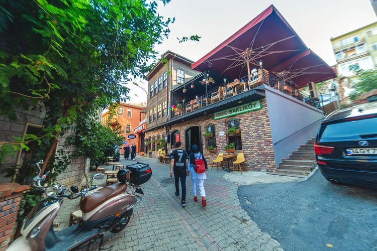 Estoy frente a una cafetería del barrio de Bakırköy con una terraza elevada, símbolo de la vibrante vida social de Estambul.
