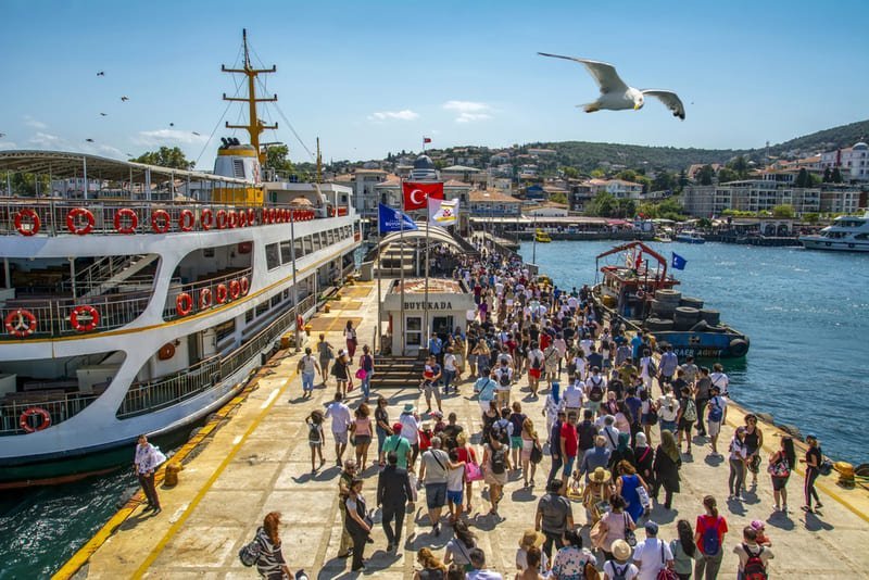 Przystań Eminönü w Stambule z promem Şehir Hatları, tłum pasażerów, flaga turecka i lecąca mewa