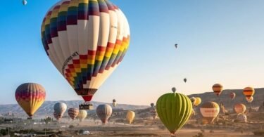 Colorful hot air balloons at sunrise flying over fairy chimneys and valleys of Cappadocia Turkey excursion from Istanbul