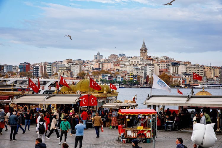 Estoy frente al concurrido muelle de Eminönü, con la Torre de Gálata del siglo XIV al fondo y vendedores ambulantes de comida.