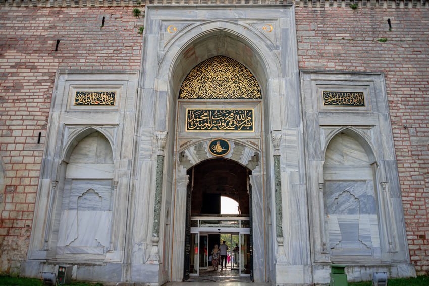 Ce qui attire mon attention, c'est la porte impériale Bâb-ı Hümâyun du palais de Topkapi, une haute arche en marbre décorée d'inscriptions coraniques dorées et d'une tughra de l'époque ottomane. L'ensemble incarne la solennité de cette entrée du XVe siècle, seuil du pouvoir impérial et symbole de la grandeur architecturale d'Istanbul.