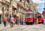 I walk along İstiklal, Istanbul's flagship avenue, where 19th-century red trams run through dense crowds against a backdrop of historic buildings.