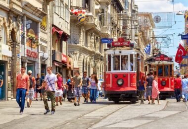 I walk along İstiklal, Istanbul's flagship avenue, where 19th-century red trams run through dense crowds against a backdrop of historic buildings.