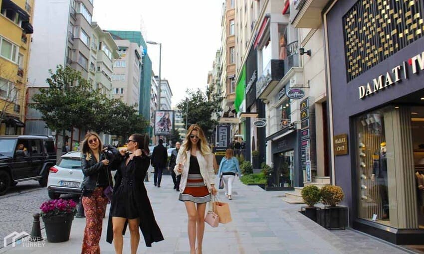Scène de shopping dans une rue chic du quartier de Nişantaşı à Istanbul, bordée de boutiques de luxe et fréquentée par une clientèle à la mode.