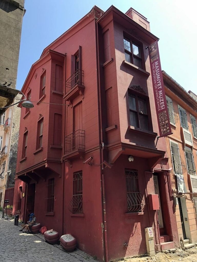 Facciata rossa del Museo dell'Innocenza a Istanbul, edificio ad angolo su una strada acciottolata. Architettura antica, striscione verticale e atmosfera letteraria.