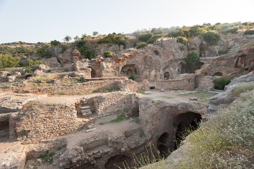 Vestiges d'anciennes maisons en pierre disséminées sur un versant rocheux, avec des grottes voûtées en briques, des conduites d'eau en terre cuite et les fondations d'habitations de l'élite romaine datant du Ier au VIIe siècle après J.-C.