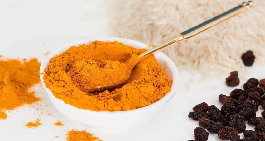 Bol de zerdeçal (curcuma), l'épice utilisée pour colorer le zerde, un dessert ottoman à base de riz servi en 1539, avec du riz et des raisins secs en arrière-plan.