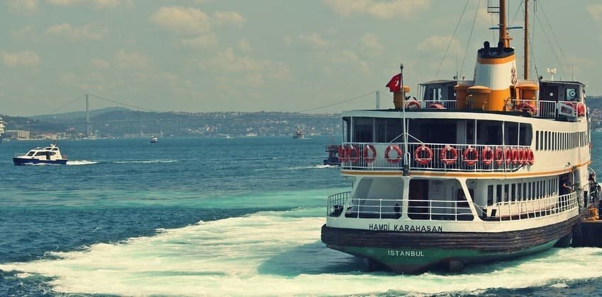 Tradycyjny prom Şehir Hatları pływający po Bosforze w Stambule z turecką flagą i widokiem na cieśninę