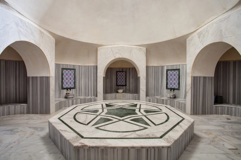 Wnętrze tradycyjnego hammamu w Stambule z ośmiokątnym marmurowym göbek taşı i osmańskimi arkadami